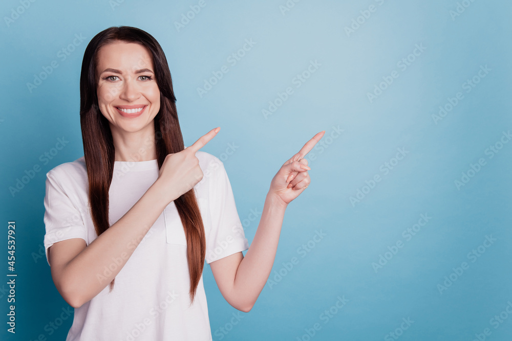 Photo of young woman gesturing with fingers showing empty space isolated over blue background Photo of young woman gesturing with fingers showing empty space isolated over blue background