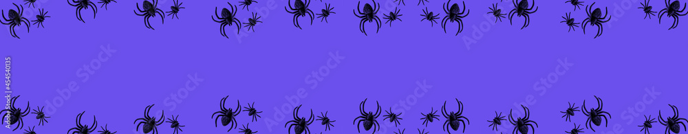 Flat lay banner of black horror spiders of different sizes directed in different directions on purple backdrop with copy space. Halloween decoration spooky background concept for holidays