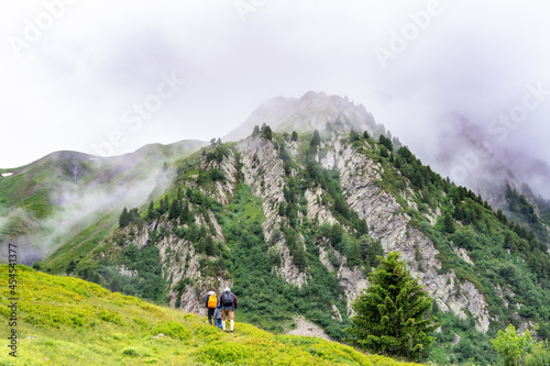Family with children hiking in high mountains in French Alps in cloudy summer weather. Travel lifestyle concept.