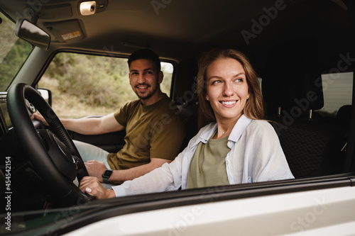 Beautiful young couple sitting on front passenger seats and driving a car