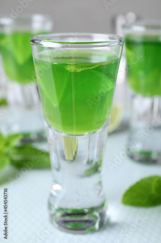 Delicious mint liqueur with lime on table, closeup