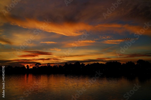 Sunset Paradise with red and blue sky, cloud, village and reflection on the river. Nature background concept with copy space, low key.