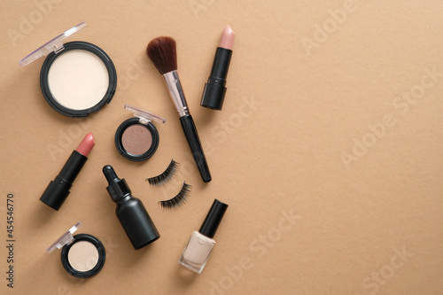 Makeup cosmetic products and accessories on brown background. Top view, flat lay. Beauty and fashion concept.