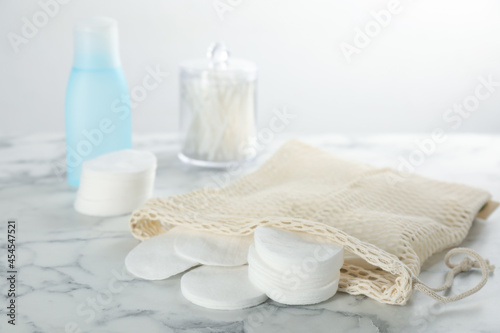 Cotton pads and makeup removal product on white marble table