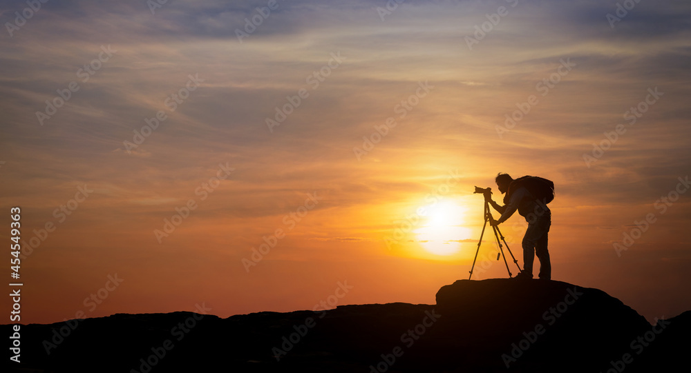 Silhouette of photographer shoots with sunset background.