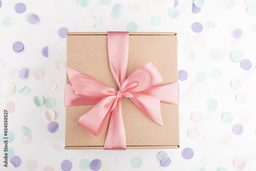 present gift box with pink bow with festive confetti. Birthday, weeding, Christmas holiday and congratulation concept. Flat lay style.