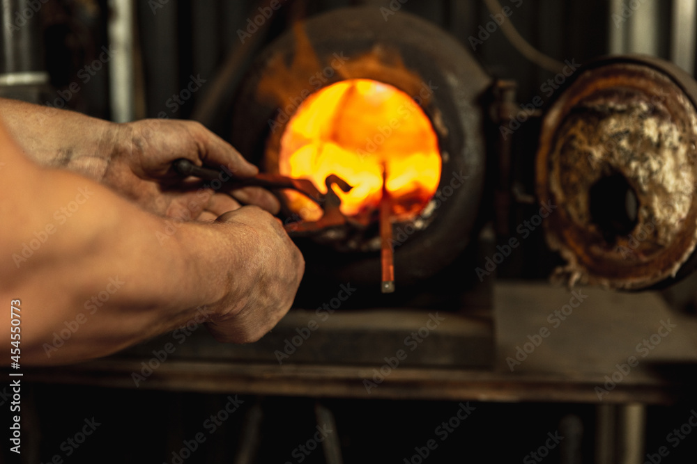 Close-up working powerful hands of male blacksmith making red hot metal in furnace, horn. Work process of heating metal in smithy. Concept of labor, retro professions, family business Close-up working powerful hands of male blacksmith making red hot metal in furnace, horn. Work process of heating metal in smithy. Concept of labor, retro professions, family business