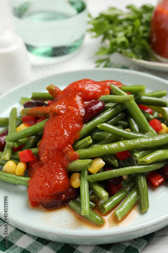 Delicious salad with green beans and tomato sauce served on table, closeup