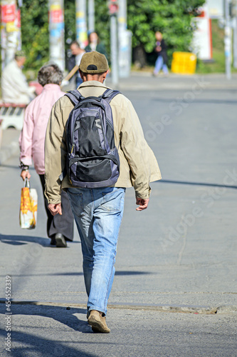 A man with a backpack walks along the city sidewalk © vladimir subbotin