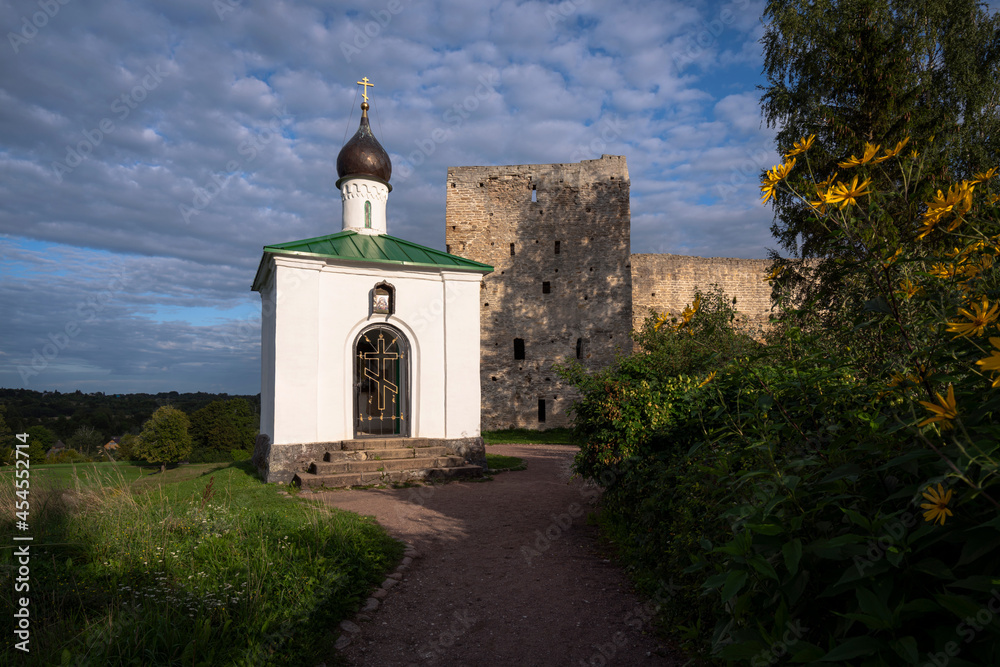 View of the Chapel of the Korsunskaya Icon of the Mother of God against the background of the Talavskaya Tower and the wall of the Izborsk fortress on a sunny summer evening, Izborsk, Pskov region