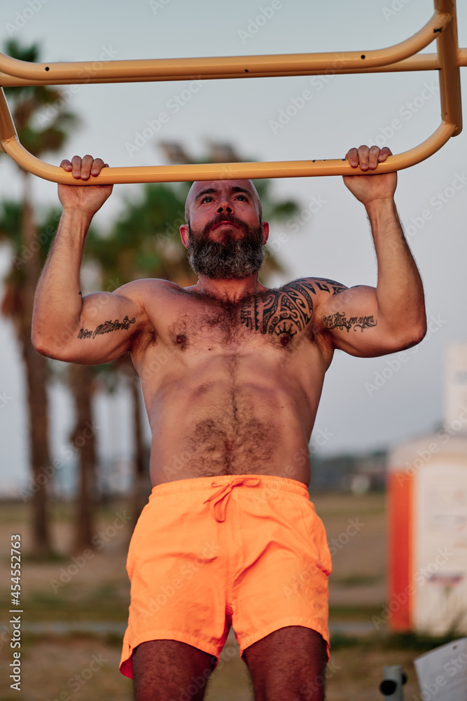 Strong man doing pull-ups exercise during workout outdoors. Strong man doing pull-ups exercise during workout outdoors.