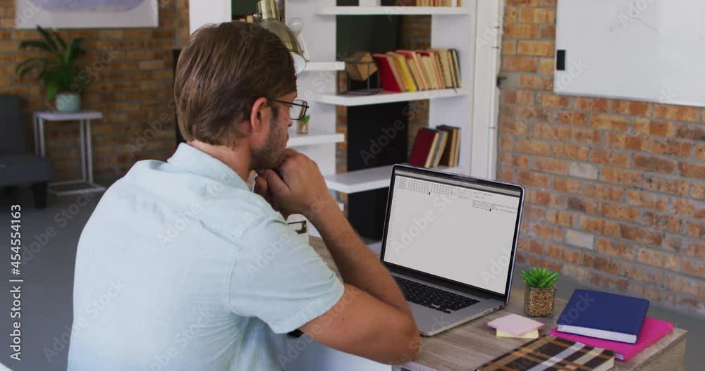Caucasian man sitting at desk watching coding data processing on laptop screen Caucasian man sitting at desk watching coding data processing on laptop screen