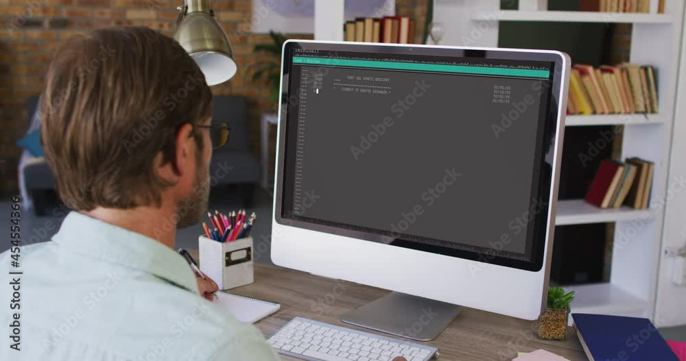 Caucasian man sitting at desk watching coding data processing on computer screen Caucasian man sitting at desk watching coding data processing on computer screen