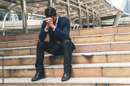 Businessman bankruptcy and debt with hands cover face while sitting on the stairs.Unemployed businessmen frustrated and desperate to find work. Concept business people failure and unemployment problem