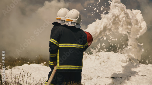 Firemen extinguishing fire in field