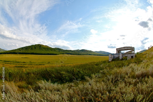 Beautiful landscape with a field, mountains and an abandoned building in Khakassia