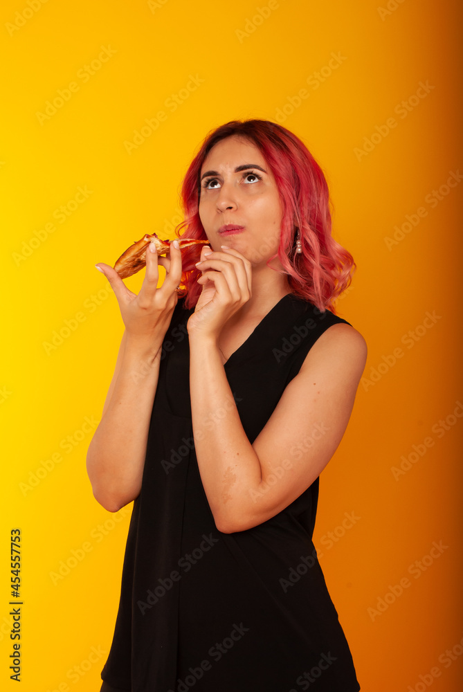 a girl of European nationality greedily looks at a piece of pizza wants to eat it on a yellow background with a place for the text a girl of European nationality greedily looks at a piece of pizza wants to eat it on a yellow background with a place for the text