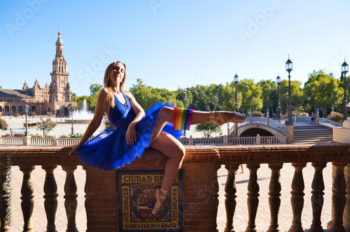 classical ballet dancer and lesbian leaning on a railing in a park. she is wearing the gay pride flag tucked into her shoes. Concept of homosexuality and ballet
