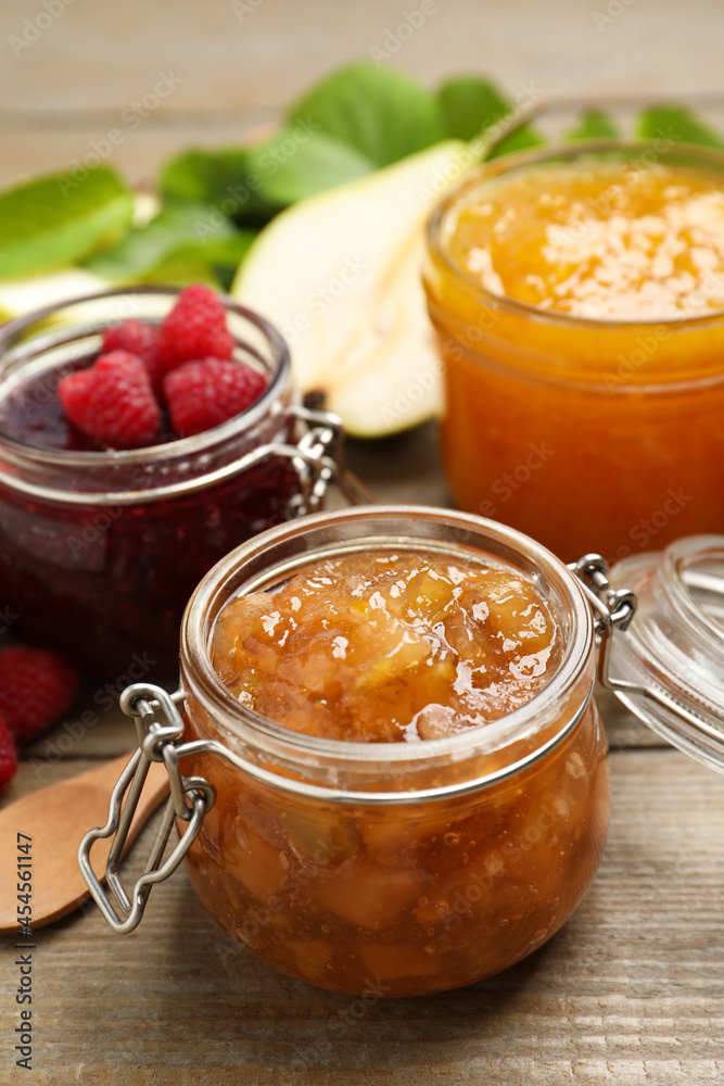 Jars with different jams and fresh fruits on wooden table Jars with different jams and fresh fruits on wooden table