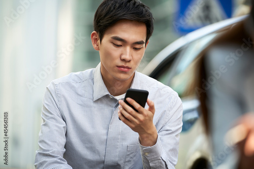 Принти на полотні young asian business man using cellphone outdoors