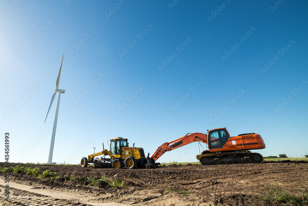 A wind turbines and other heavy machinery used for the assembly of more turbines, in a wind energy farm A wind turbines and other heavy machinery used for the assembly of more turbines, in a wind energy farm