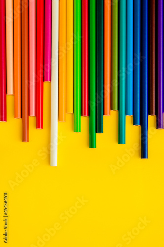 Colored pencils are arranged in a row on a light yellow background.