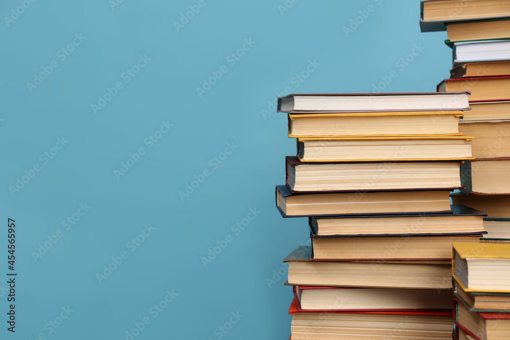 Many hardcover books on turquoise background, space for text. Library material - obrazy, fototapety, plakaty 