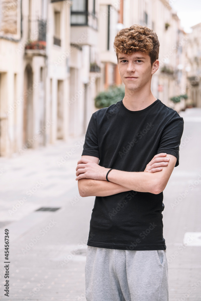 Fototapeta premium Teen boy with curly hair walking down the street
