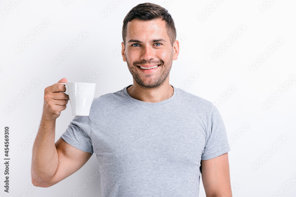 Waist up portrait view of the handsome man standing and holding a cup of morning tea or coffee and smiling while looking at the camera. Stock photo Waist up portrait view of the handsome man standing and holding a cup of morning tea or coffee and smiling while looking at the camera. Stock photo