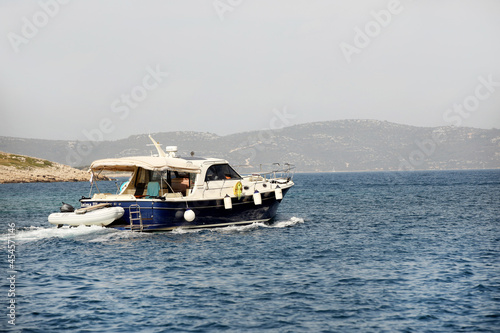 Motor yacht running along the blue sea along the shore. Adriatic sea of Mediterranean area. Dalmatian region of Croatian country. Exclusive recreation on the water for active people.