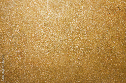 Golden rough surface covered with sequins. Beautiful festive pattern for holidays. Backdrop for Christmas text. Horizontal photo.
