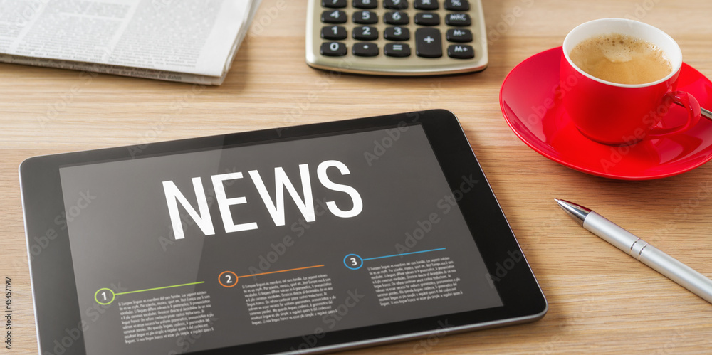 A tablet on a desk with the headline News A tablet on a desk with the headline News