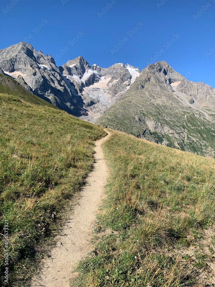 trail for hikers. in the background the peaks of the Meije. la Grave, France.