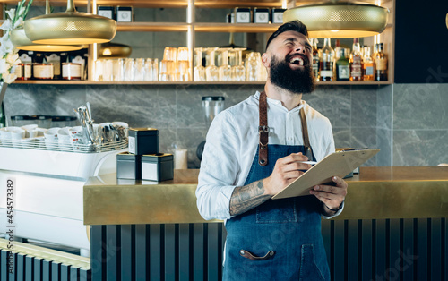 Canvas Print Cheerful Smiling Barista Doing an Inventory of the Products in a Cafe