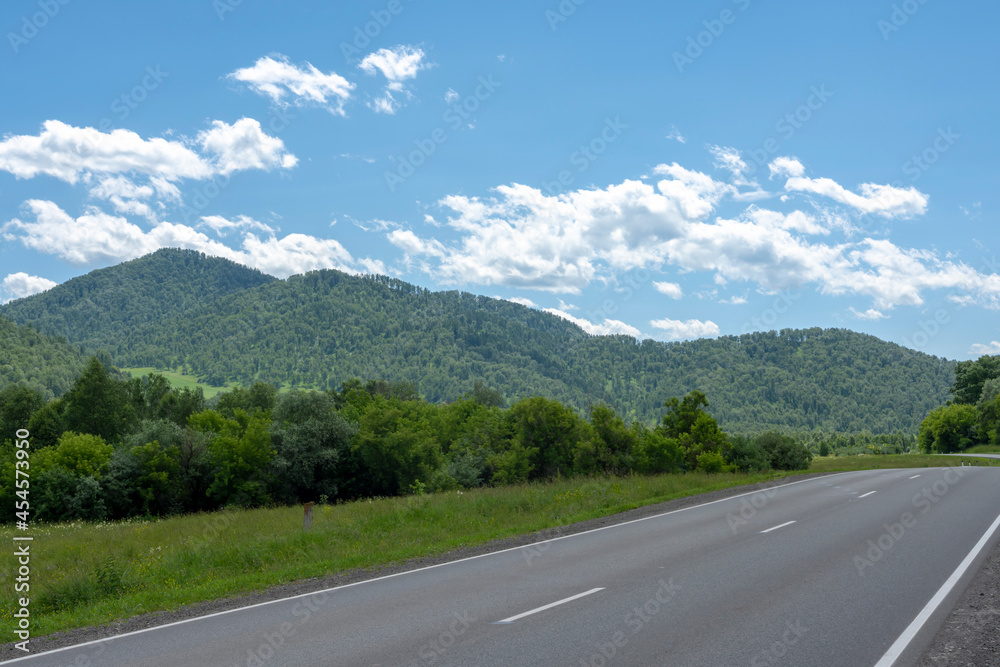 highway road and mountain peaks on the background of a blue sky with clouds highway road and mountain peaks on the background of a blue sky with clouds