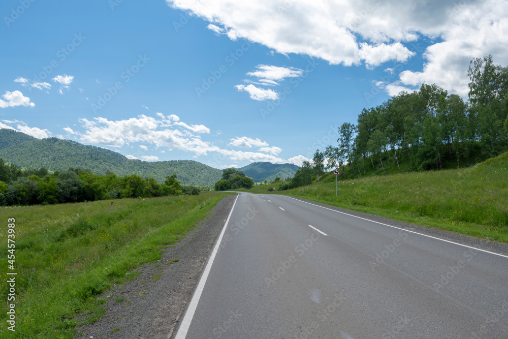 highway road and mountain peaks on the background of a blue sky with clouds highway road and mountain peaks on the background of a blue sky with clouds