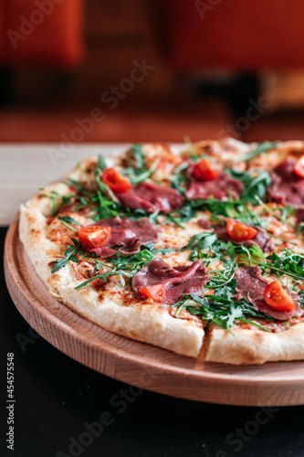 Pizza with cherry tomatoes, rucola and salami in bar environment