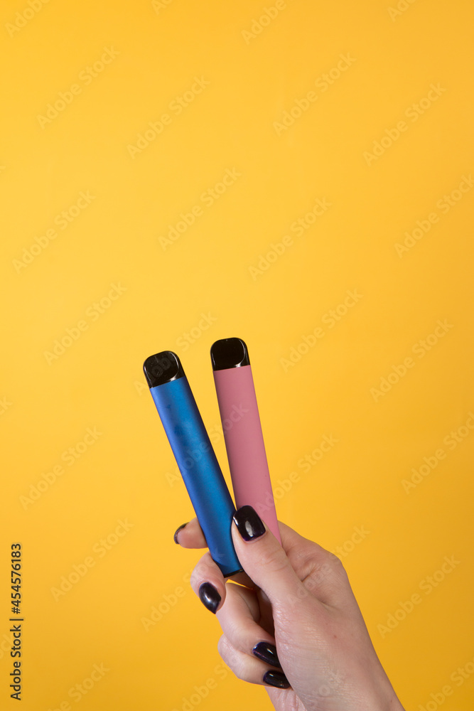Female hand holding two vape sticks Female hand holding two vape sticks