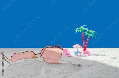 Fototapeta Naklejka Na Ścianę i Meble -  Sunglasses in the sand. Advertising of cosmetic products. Blank background. Sea white sand with a close-up piece of wood. Cosmetics and product concept