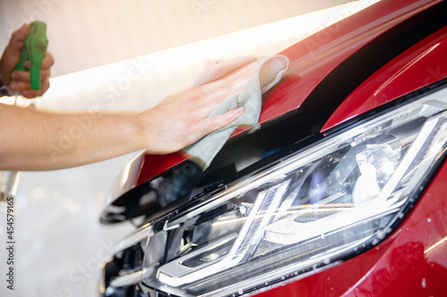 Manual car wash, man working preparation of red body for pasting protective vinyl film