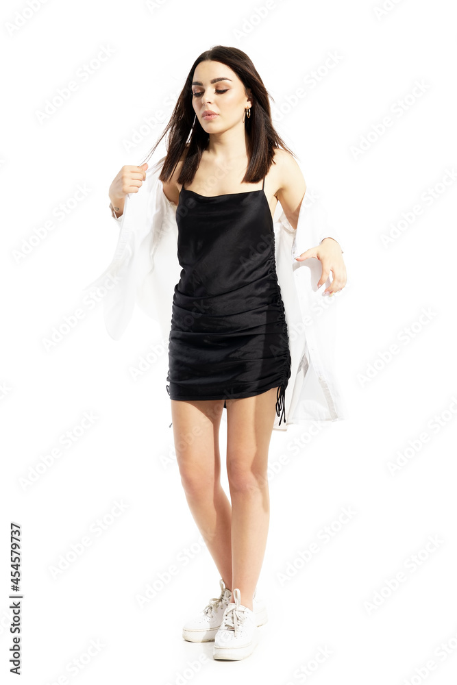 Young black hair woman in black satin dress undressing white shirt spontaneous. Full body portrait isolated on white background Young black hair woman in black satin dress undressing white shirt spontaneous. Full body portrait isolated on white background