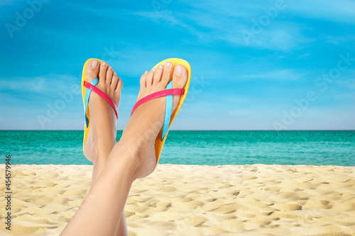 Woman wearing stylish flip flops resting on sandy beach and enjoying beautiful seascape, closeup