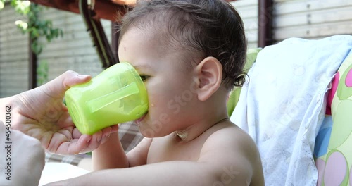 Portrait of a little boy who sits on a child's chair. Happy child drinks milk, kefir or dairy products from a cup. Correct and natural nutrition for children