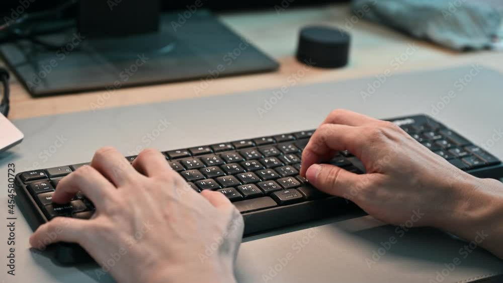 Hand of employee typing document data with wireless keyboard on desk at the office Hand of employee typing document data with wireless keyboard on desk at the office