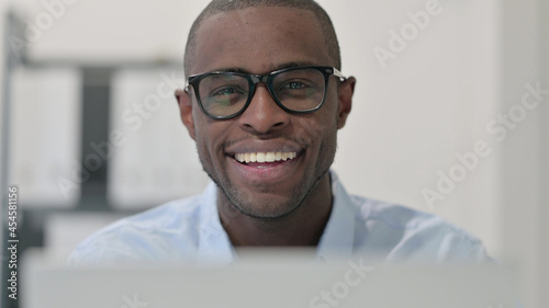 Close Up of African Man with Laptop Smiling at Camera