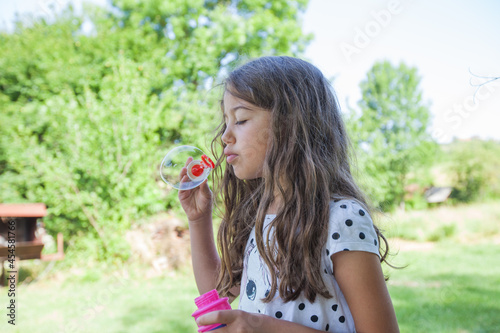 Portrait of adorable little girl blowing bubbles