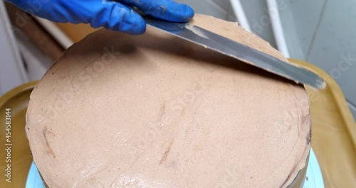 Confectioner woman is smearing cream on sides of cake using spatula, closeup view. culinary, baking and cooking food concept, home cooking