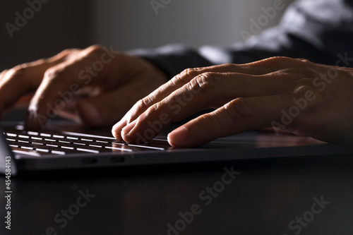 Businessman working on keyboard laptop, sitting on the table and using internet technology at workplace in office.