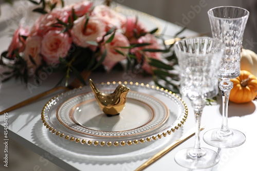 Decoration wedding table setup with golden cutlery, olive branch, porcelain plate, glass concept.