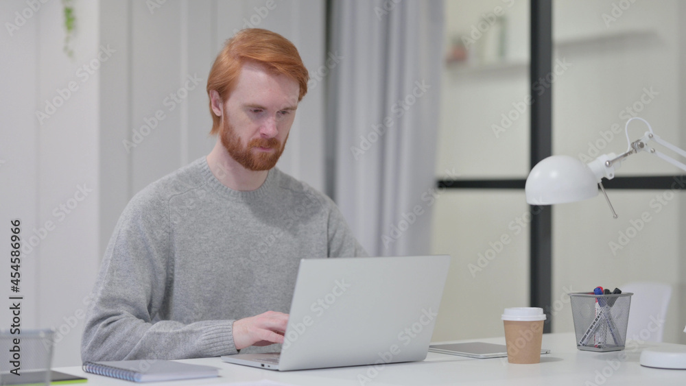 Beard Redhead Man Working on Laptop in Office Beard Redhead Man Working on Laptop in Office